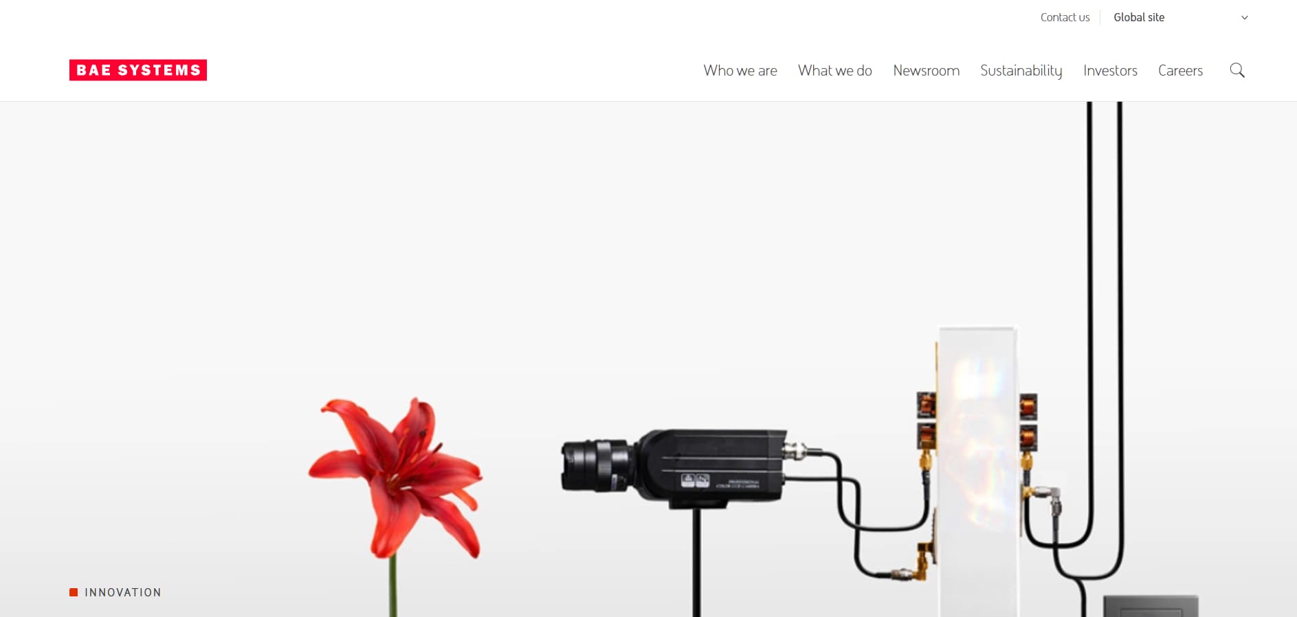 BAE Systems technology innovation banner with camera device and red flower on white background