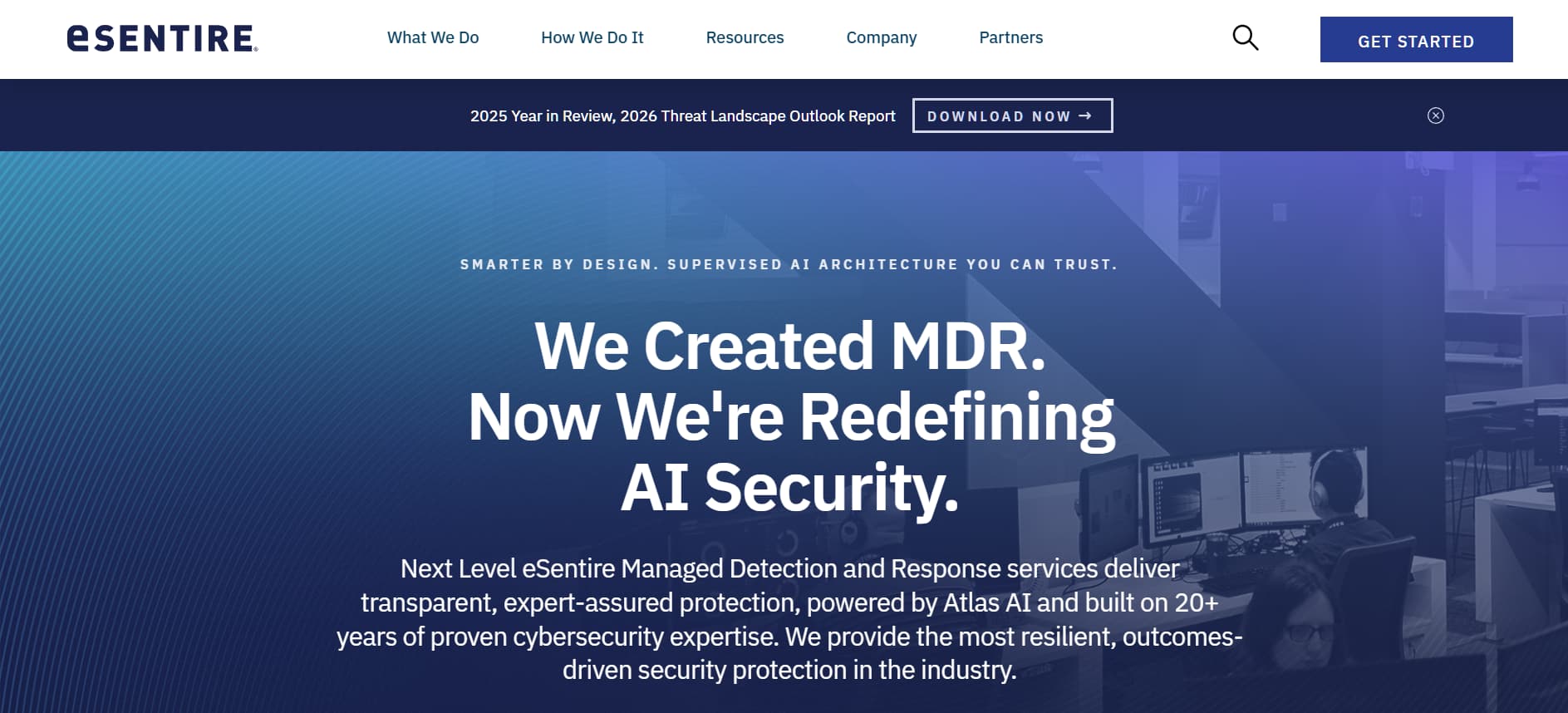 eSentire cybersecurity website homepage with blue gradient banner reading “We Created MDR. Now We’re Redefining AI Security,” navigation menu at the top, and a background image of security analysts working at computer monitors.