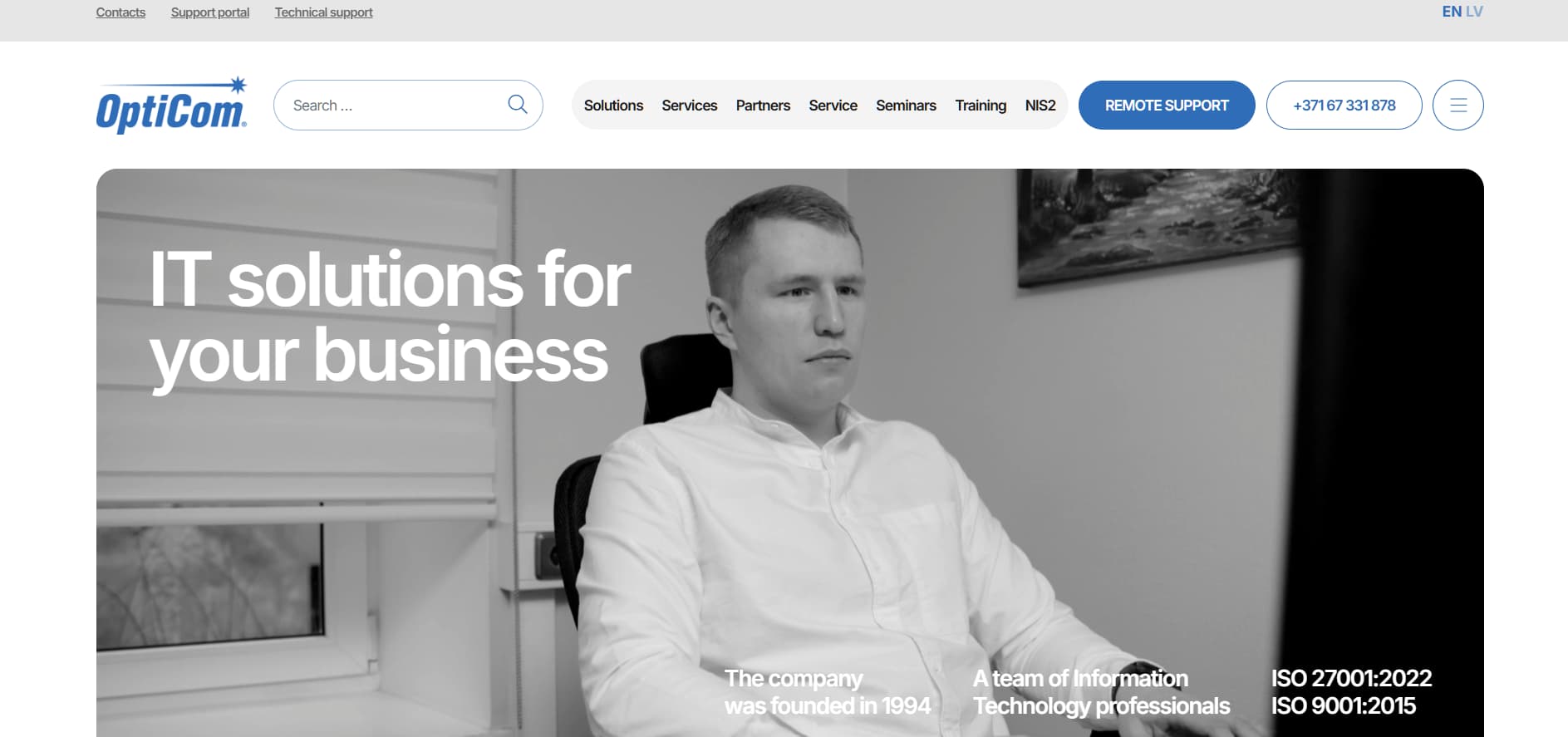Alt text: OptiCom IT solutions website homepage showing a man sitting at a desk with the headline “IT solutions for your business,” navigation menu at the top, and certification badges for ISO 27001 and ISO 9001.